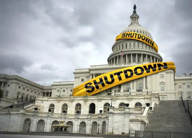 Picture of the Capitol building in Washington, DC with a yellow banner draped over it that reads 'shutdown'