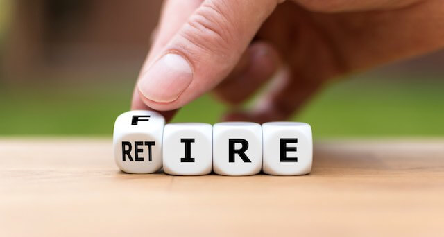 Close up of a person's hand turning the first die on a row of dice between the letter 'F' and 'RET' where the remaining three dice spell 'IRE' depicting a choice between retiring or getting fired