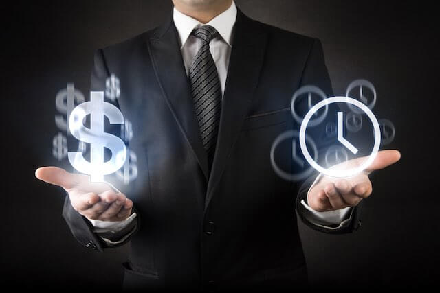 Businessman facing front with his palms turned upward holding a dollar sign in one hand and a clock symbol in the other depicting the concept of time is money, back pay or double pay