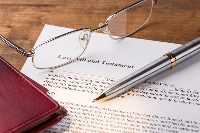 Document labeled 'last will and testament' on a desk with glass, a pen and checkbook