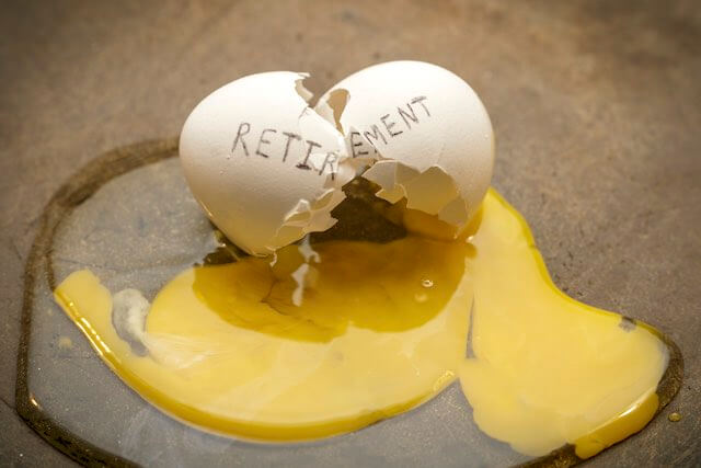 Egg labeled 'retirement' broken in half with the yolk spilled out onto the countertop depicting a broken retirement nest egg with no retirement savings