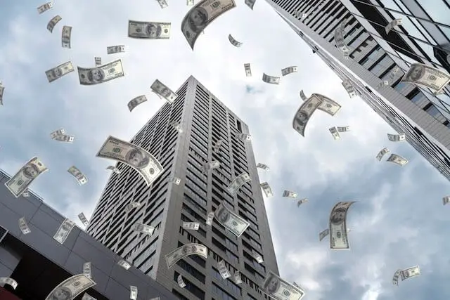 Dollars floating around in the air in a city looking up towards a skyscraper depicting locality pay