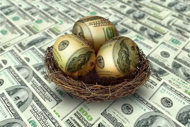 Golden eggs with Benjamin Franklin's faces imposed on them to look like $100 bills sitting in a nest on top of a spread of $100 bills depicting a retirement savings nest egg for the future