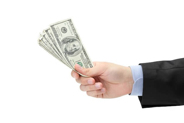 Close up of a businessman's hand holding cash against a solid white background