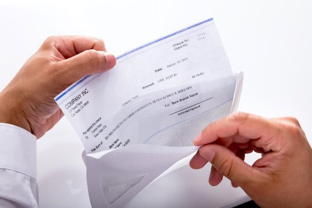 Close up of a businessman's hands opening an envelope with a paycheck in it