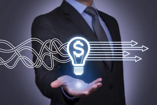 Businessman with his hand outstretched and palm facing upward underneath an illustration of a lightbulb lit up with a dollar sign inside of it depicting ideas about finance/money