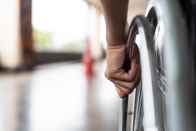 Closeup of a man's hand on the wheel of a wheelchair