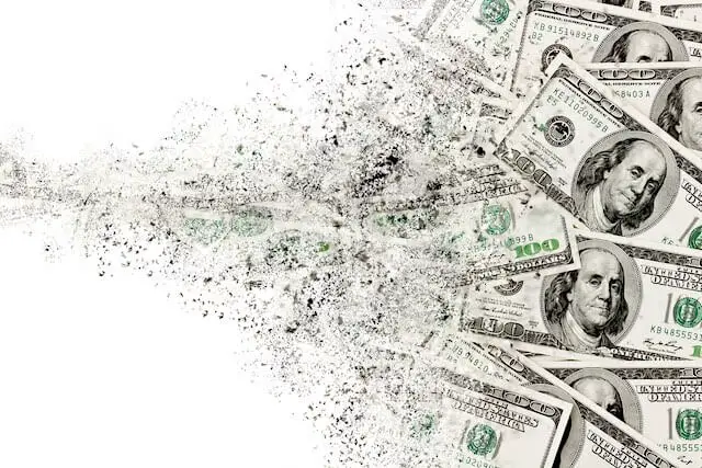 Scattering of $100 bills appearing to dissolve against a solid white background depicting currency inflation