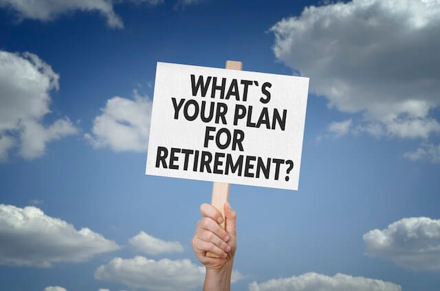 Close up of a person's hand holding up a sign that reads 'what's your plan for retirement?'