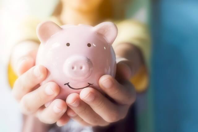 Close up of a woman's hands holding a pink piggy bank