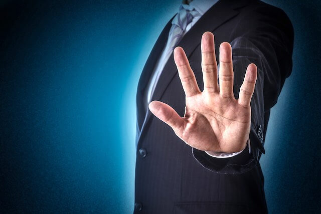 Close up of a businessman's hand putting his palm forward in a stop or hold on gesture