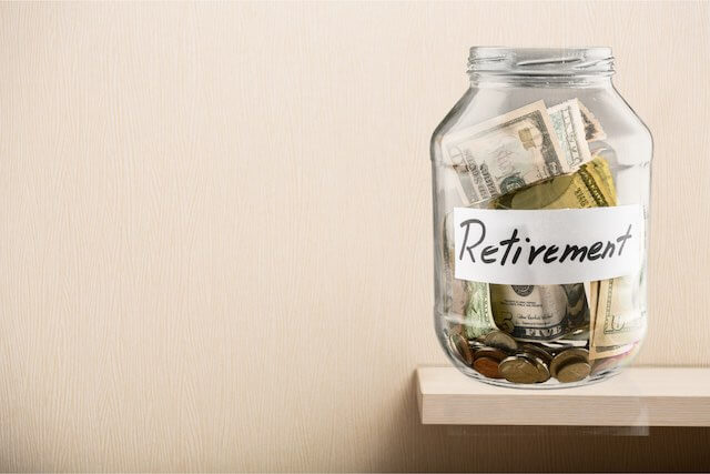 Glass filled with money labeled 'retirement' sitting on a shelf
