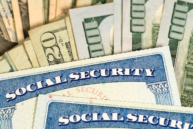 Close up of two Social Security cards on top of a spread of cash