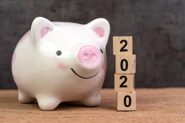 Piggy bank next to a vertical stack of wooden block letters that spell '2020'