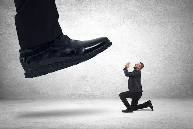 Image of a giant boss' foot about to stomp on a tiny sized employee/businessman as he begs for mercy