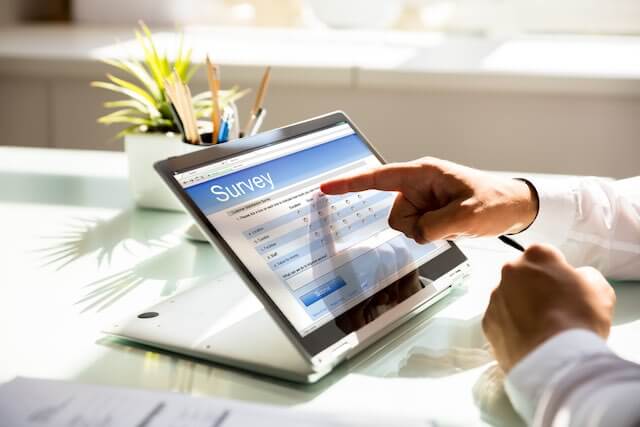 Close up of a businessman tapping responses to an online survey on a tablet as he sits at a workstation