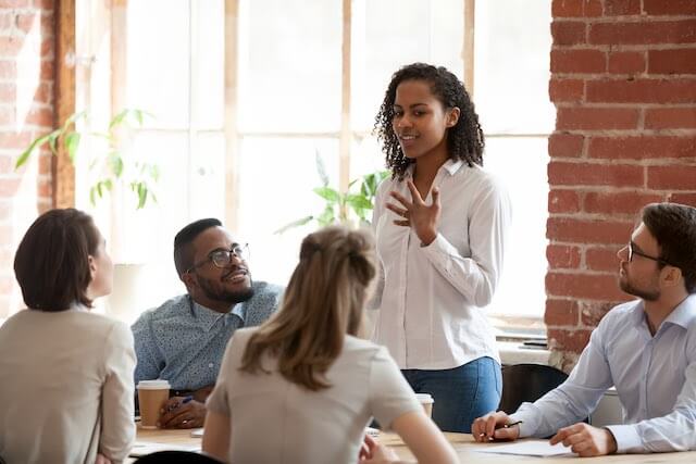 Young businesswoman speaks to her team at a staff meeting in an office conference room