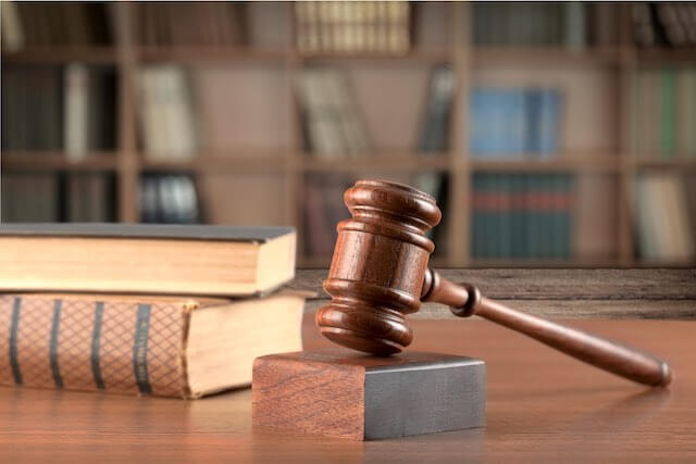 Wooden judge's gavel on a desk next to two law books