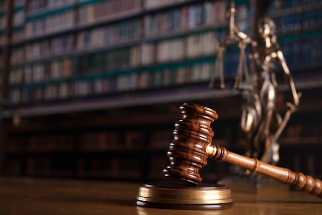 Wooden judge's gavel with a justice statue in the background