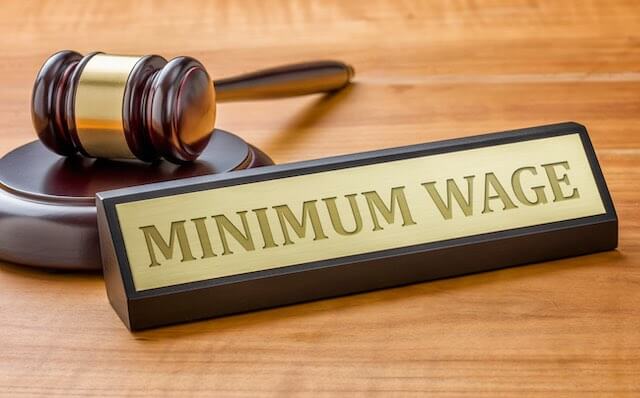 Judge's gavel beside a desk plaque that reads 'minimum wage'