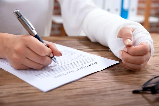 Close up of an injured woman filling out a work injury claim form