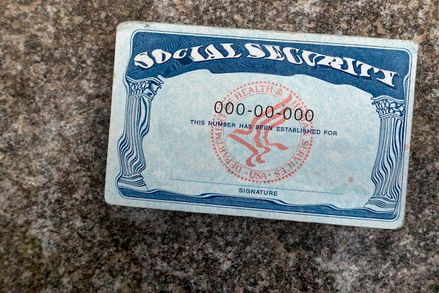 Social Security card on a granite surface where the words 'Social Security' at the top of it appear slightly blurred/distorted
