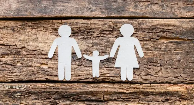 Paper cutout of a man, woman and child pictured on a wooden surface