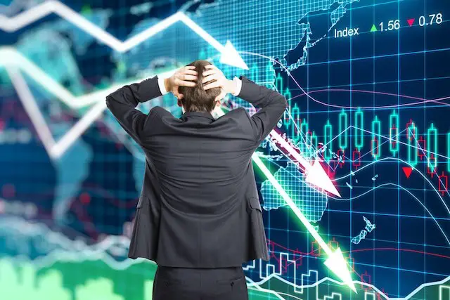 Businessman with his hands clasped behind his head appearing worried as he looks at a financial chart showing declining stock market returns