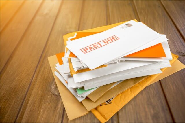 Stack of lets on a wooden surface with the one on top labeled 'past due'