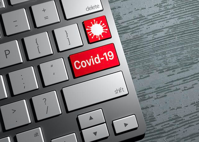 Slate colored computer keyboard with a closeup on a red and white key that reads 'cover-19' with a Coronavirus icon on a second red and white key above it