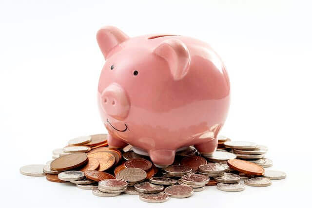 Piggy bank sitting on top of a pile of coins against a solid white background