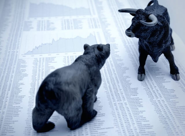 Small figurines of a bull and a bear pictured on top of the financial section of a newspaper