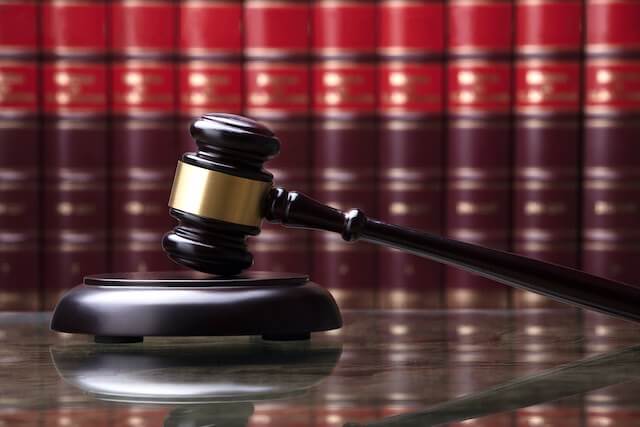 Wooden judge's gavel on a desk with a row of law books in the background