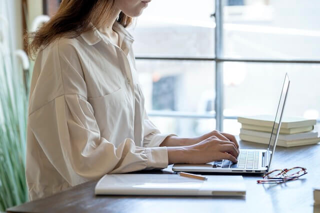 Young woman teleworking on a laptop computer at a desk in front of a window