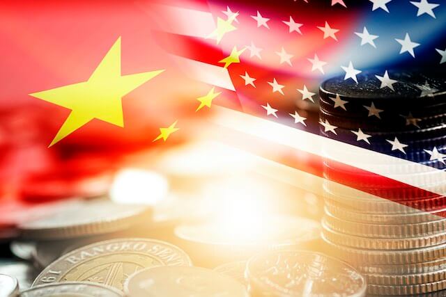 Collage style image of the Chinese and American flags with an image of stacks of coins intermingled between the two flags