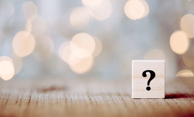 Question mark on a wooden block pictured sitting on a wooden surface