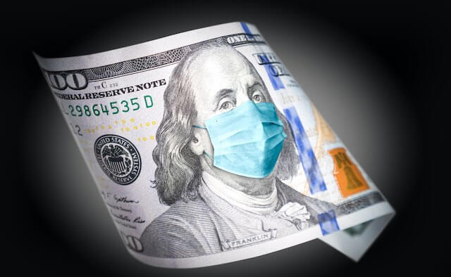 $100 bill with the image of Benjamin Franklin wearing a surgical face mask pictured against a black background