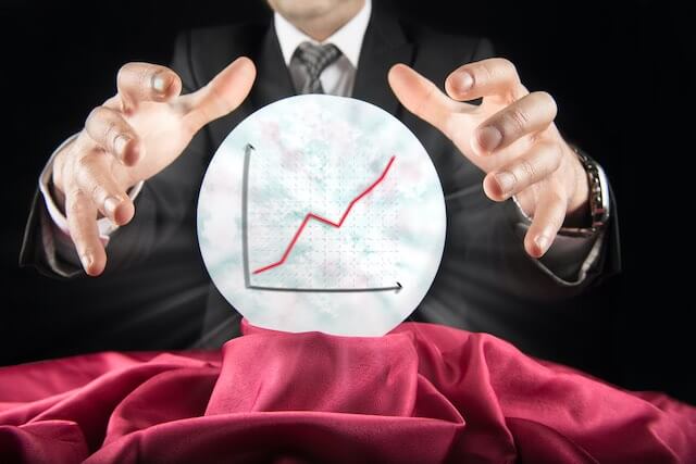 Businessman holding his hands open around a crystal ball with a rising financial graph inside of it