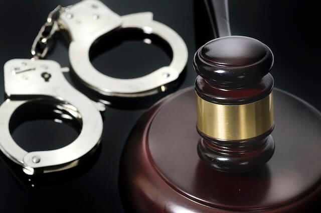 Wooden judge's gavel next to a pair of handcuffs