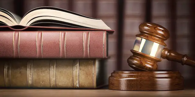 Wooden judge's gavel on a desk next to a stack of law books