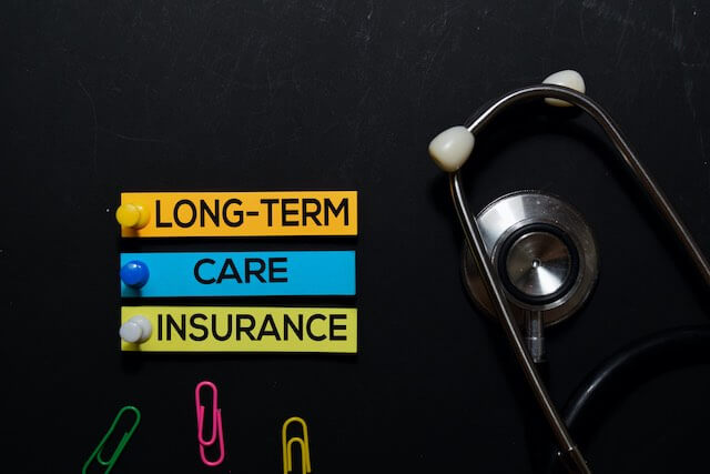 Words 'long-term care insurance' on a black background next to a stethoscope and paper clips