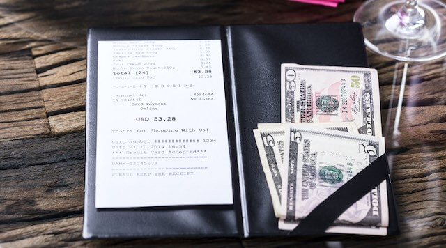 Bill folder on a restaurant table with the bill and money to pay the tab