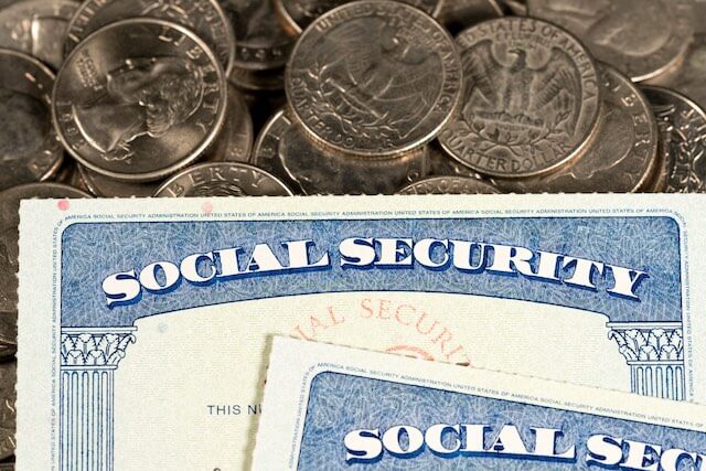 Two Social Security cards pictured on top of a spread of quarters