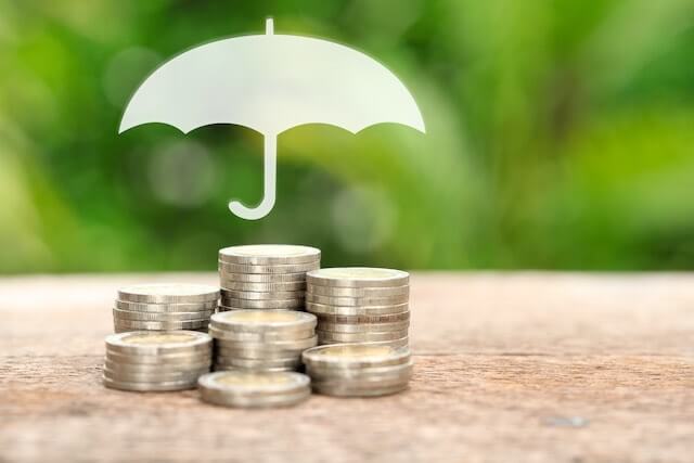 An umbrella is pictured over small stacks of coins protecting them
