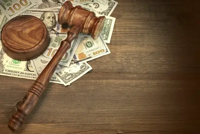 Wooden judge's gavel on a spread of cash on a wooden surface