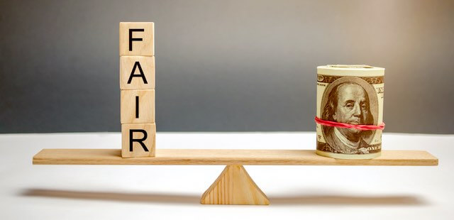 Wooden seesaw type scale perfectly level with wooden block letters on the left side in a vertical stack spelling 'fair' and a roll of cash on the other side