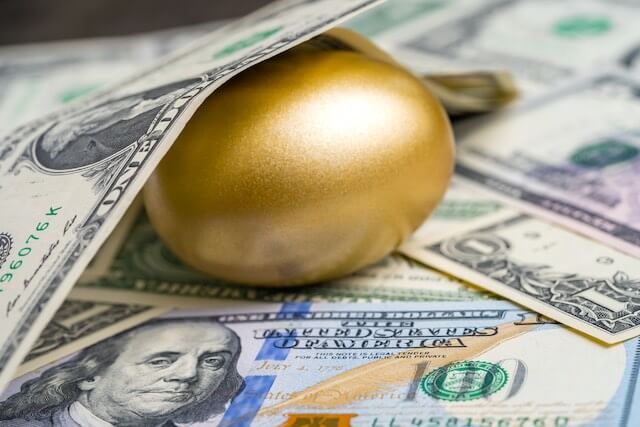 Golden egg on top of a spread of cash with a $1 bill covering the top of it