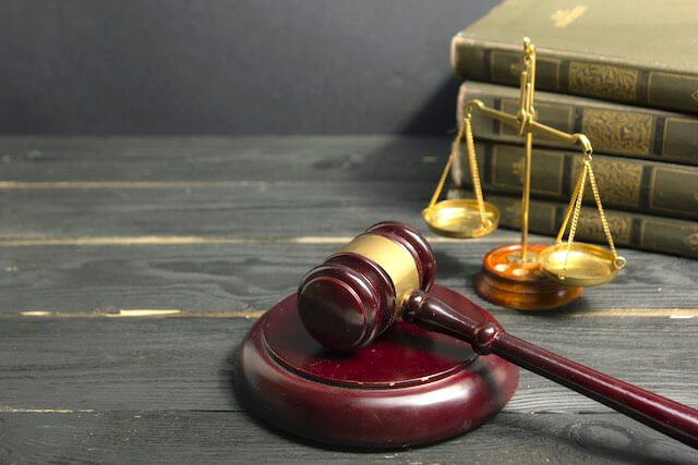 Wooden judge's gavel, justice scales and a stack of law books on a wooden surface