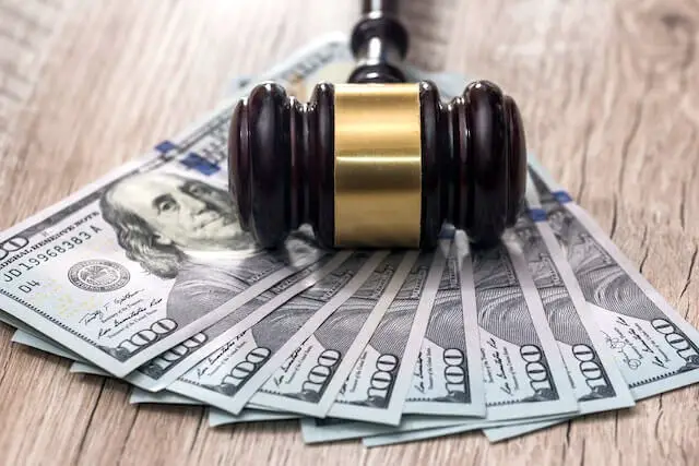 Wooden judge's gavel lying on top of a spread of cash ($100 bills)