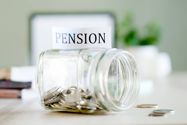 Jar half filled with coins lying on its side with a label over the top of it that reads 'pension'